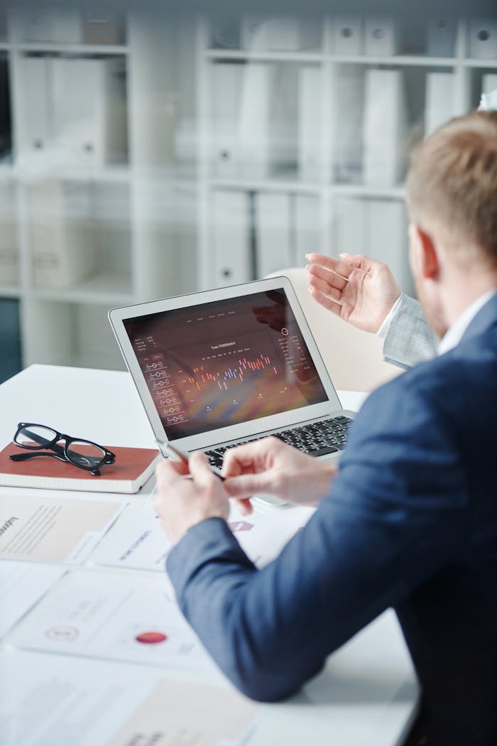 Two professionals discussing a financial analysis on a laptop in a modern office.